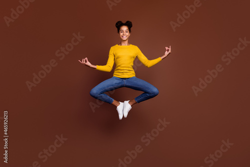 Full length photo of teen girl jump do asana wear shirt jeans sneakers isolated on brown color background