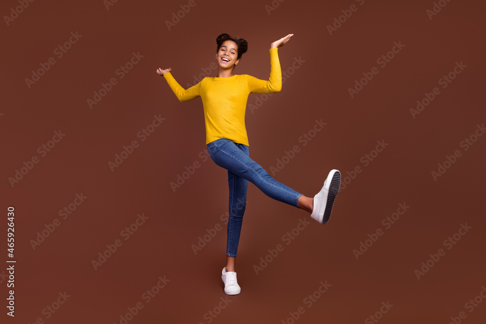 Full length photo of small girl dance wear sweater jeans footwear isolated on brown color background