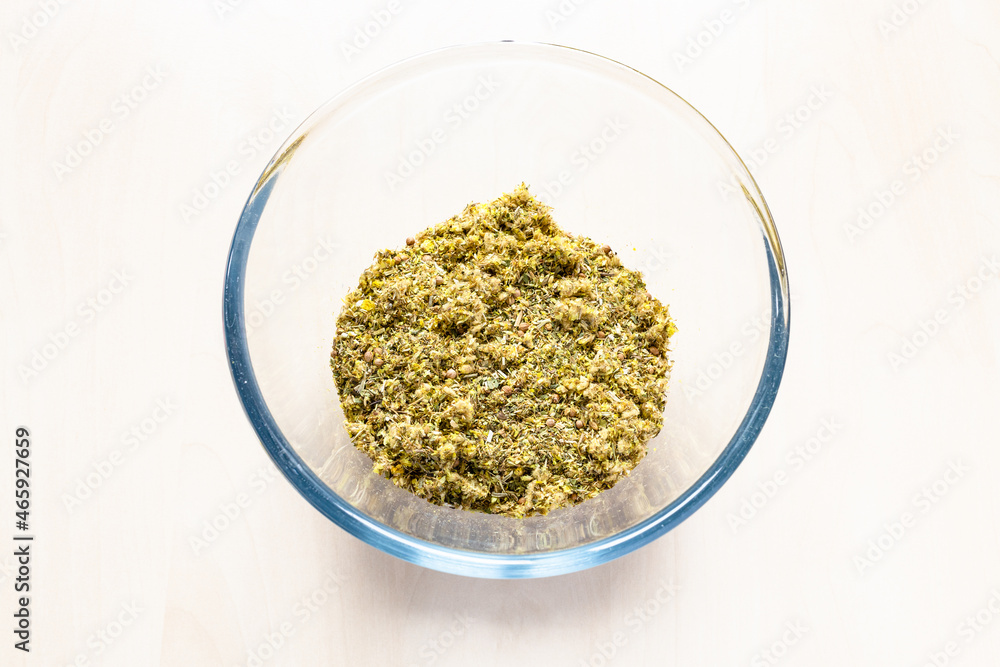 above view of dried crushed medicinal herbs and plants in glass bowl on light brown table above view of dried crushed medicinal herbs and plants in glass bowl on light brown table