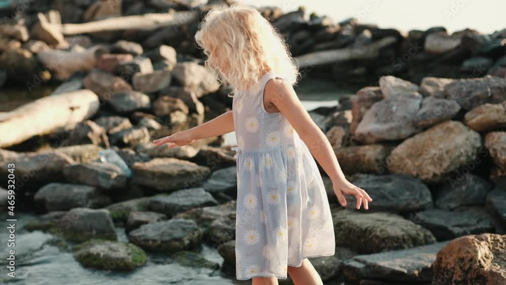 Happy little curly girl playing on the beach on sunrise Happy little curly girl playing on the beach on sunrise