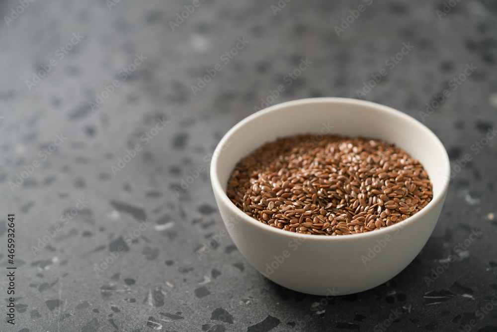 Flax seeds in white bowl on terrazzo surface with copy space Flax seeds in white bowl on terrazzo surface with copy space