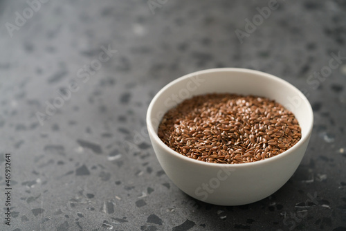 Flax seeds in white bowl on terrazzo surface with copy space