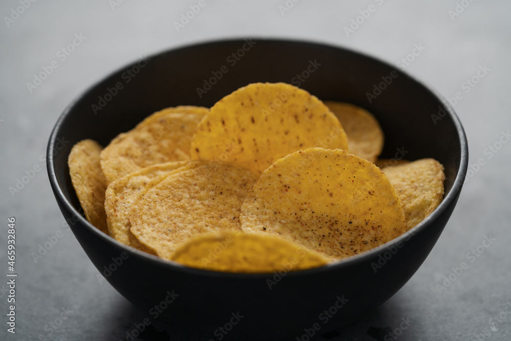 Round nachos in black ceramic bowl on concrete background Round nachos in black ceramic bowl on concrete background