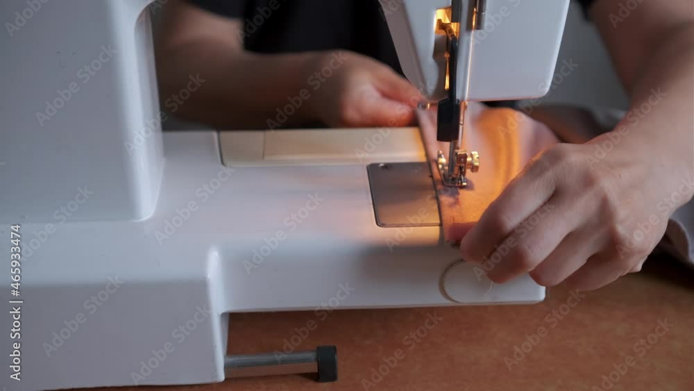 Closeup of a young woman's hands sewing with a sewing machine Closeup of a young woman's hands sewing with a sewing machine