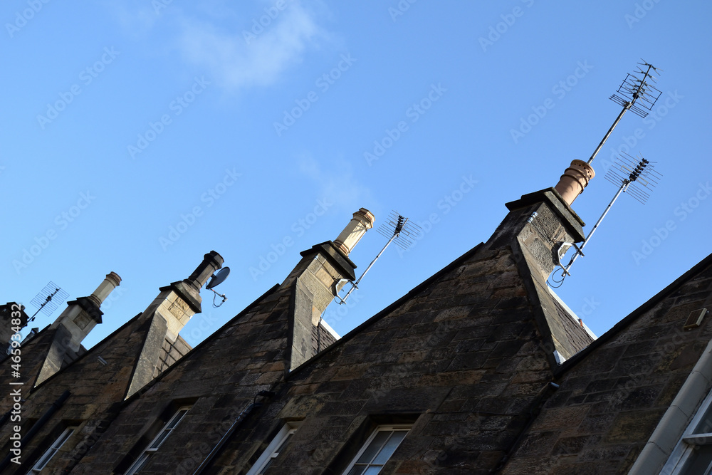 Abstract View of Old Stone Buildings & Chimneys seen from below Angled against Blue Sky