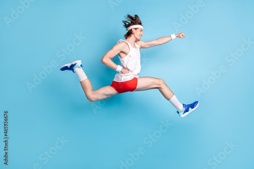 Full length profile photo of funny millennial brunet guy run wear singlet shorts sneakers socks isolated on blue background