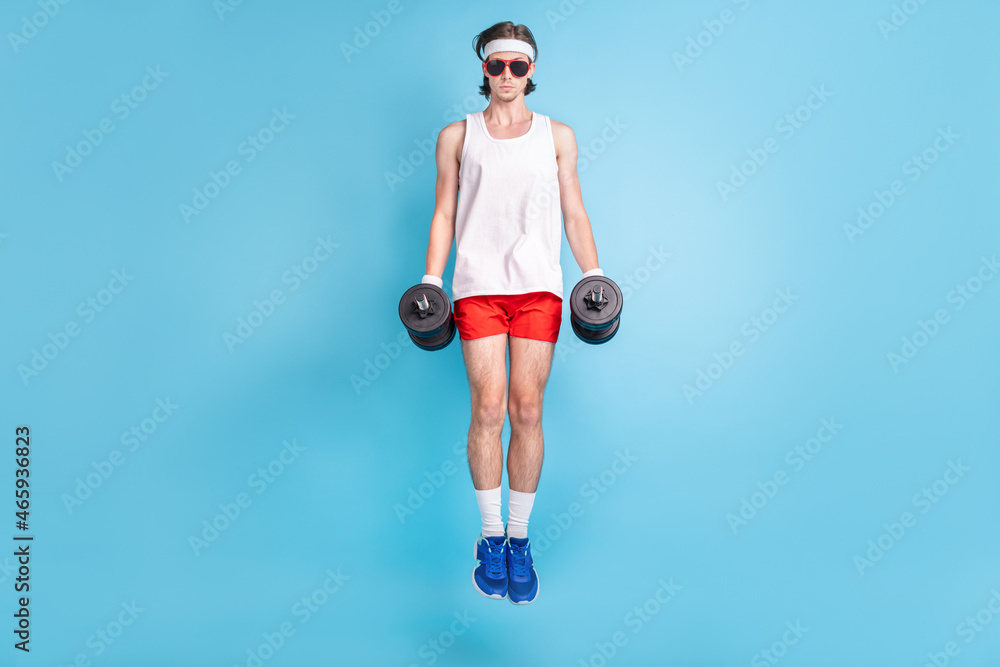 Full body photo of strong young brunet guy jump wear eywear singlet shorts sneakers socks isolated on blue background