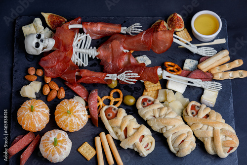 Snack Halloween Plate With Skeleton And Egyption Mummy From Food On Black Background. Flat Lay.