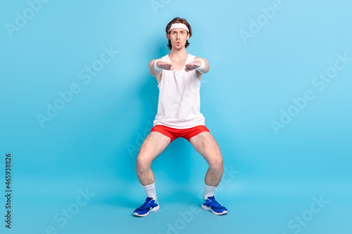 Full length body size photo man doing stretching wearing sportswear headband isolated pastel blue color background photo
