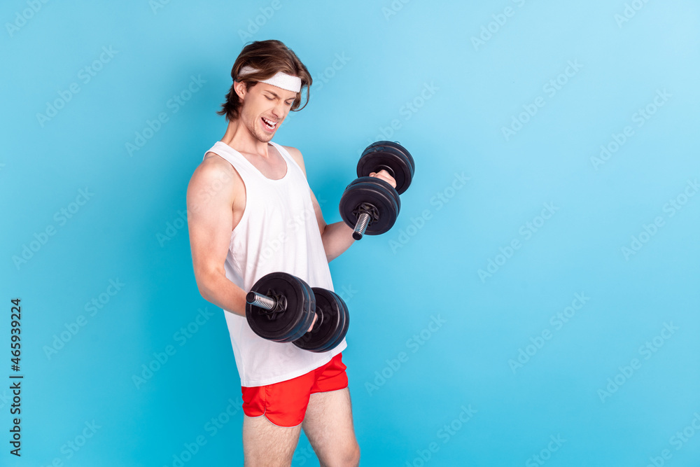 Photo portrait strong man lifting heavy dumbbells isolated pastel blue color background Photo portrait strong man lifting heavy dumbbells isolated pastel blue color background