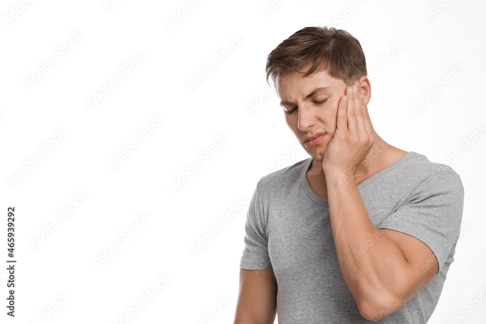 Unhappy sad attractive millennial european guy suffering from toothache, feeling unwell, touching cheek Unhappy sad attractive millennial european guy suffering from toothache, feeling unwell, touching cheek