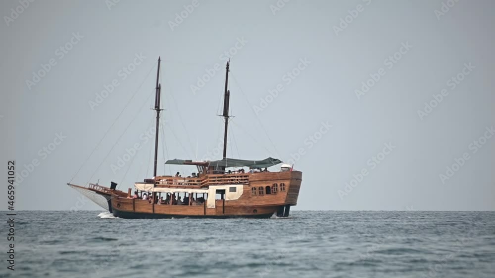 Low angle, sea-level view of wooden tourist passing by. Beautiful Adriatic Sea in summer. People taking tour along Slovenian coast. Slow motion, static shot Low angle, sea-level view of wooden tourist passing by. Beautiful Adriatic Sea in summer. People taking tour along Slovenian coast. Slow motion, static shot