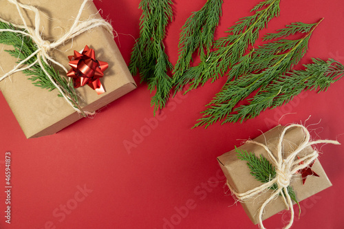 Top view two christmas gift boxes and pine tree leafs on red background concept photo copy space