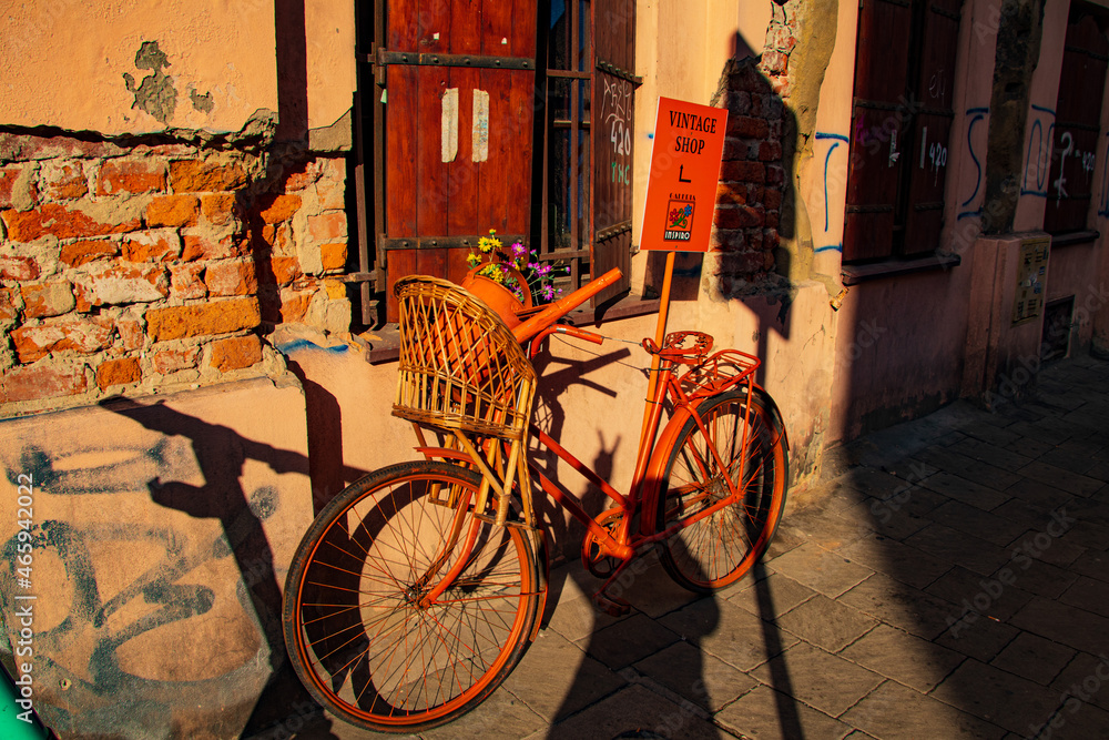 opustoszała ulica w krakowie w promieniu jesiennego słońca bez ludzi teksturowane graffiti na ścianach domów samotne stare zabytkowe rowery na drodze z kamieni ciepły pomarańczowy odcień