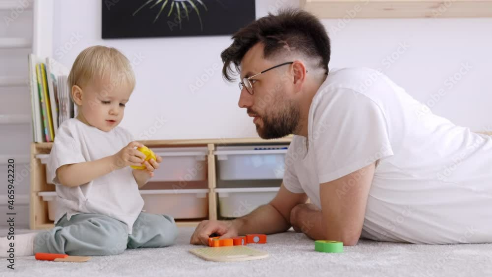 Father and Toddler Son playing together with Wood Toys in Kids Room at Home, having a Good Time Together spending Father's Day, Close Up, Real Time, Copy Space Father and Toddler Son playing together with Wood Toys in Kids Room at Home, having a Good Time Together spending Father's Day, Close Up, Real Time, Copy Space