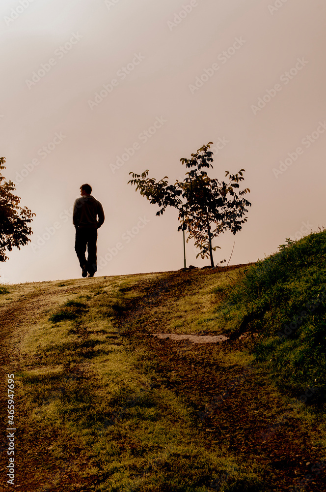 silhouette of a young man casually walking on a hill silhouette of a young man casually walking on a hill