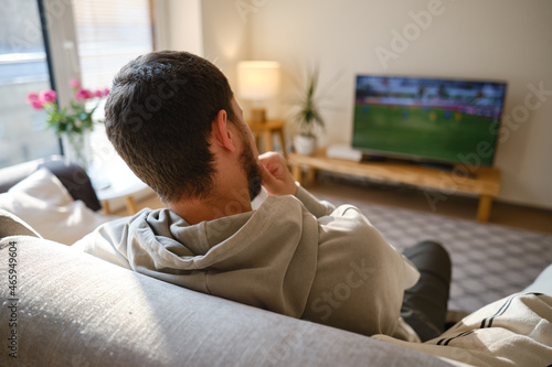 Man on the couch is watching TV. football fan watches football and rejoices at the victory. Entertainment and sports concept. Watching sports, movies on TV at home