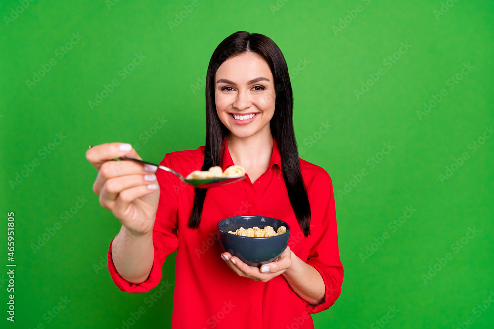 Photo of young woman happy positive smile hold plate spoon eat cereal cornflakes morning tasty isolated over green color background Photo of young woman happy positive smile hold plate spoon eat cereal cornflakes morning tasty isolated over green color background