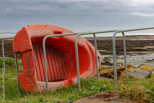 Petite annexe de bateau de couleur rouge couché sur le flanc face à la mer à Damgan en Bretagne 