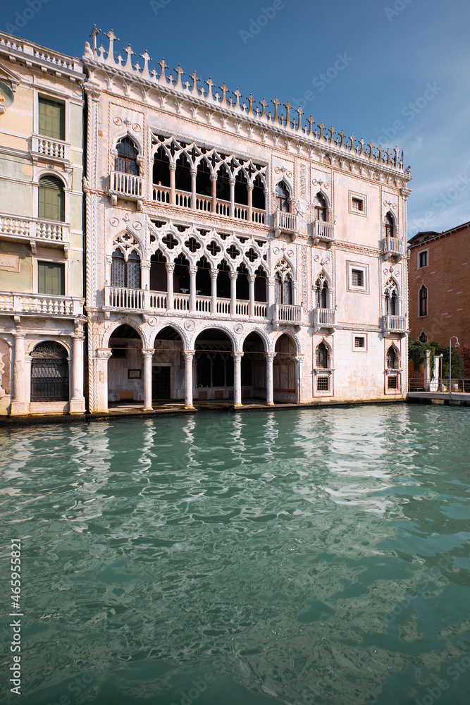 Architecture of Venice, Italy. Palazzo, historic house reflected in the water of Grand Canal. Traditional Venetian architecture. Bright sunny day with blue sky.