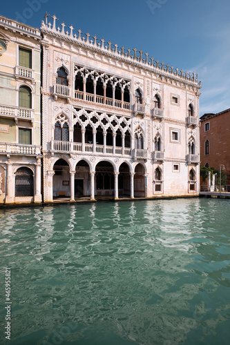 Architecture of Venice, Italy. Palazzo, historic house reflected in the water of Grand Canal. Traditional Venetian architecture. Bright sunny day with blue sky. © tilialucida