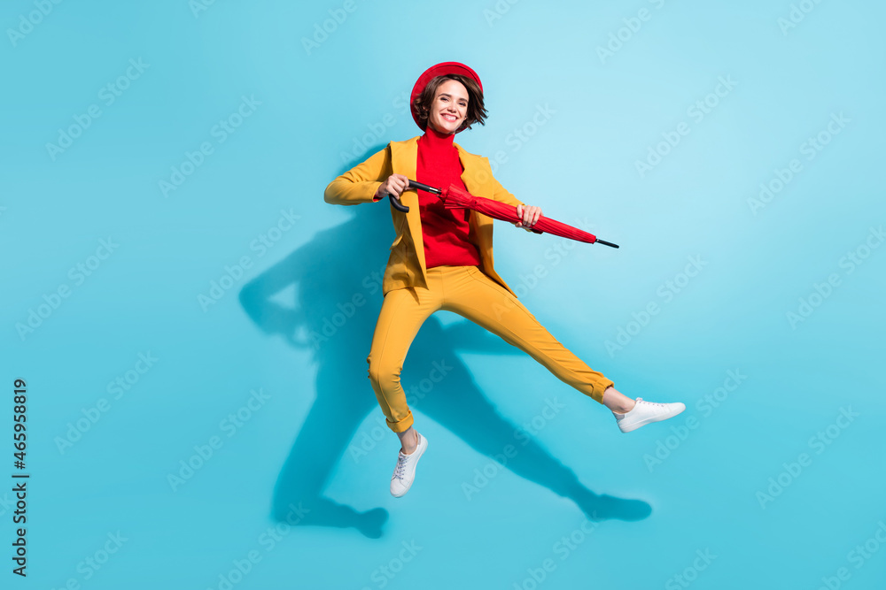 Full size photo of young girl happy positive smile jump up hold umbrella rain isolated over blue color background