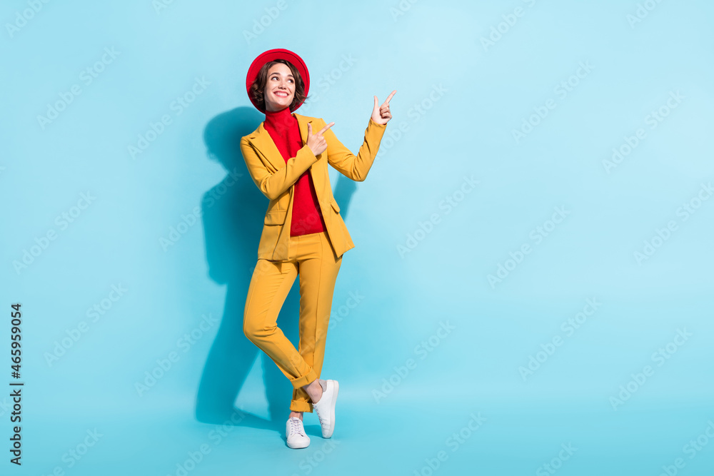 Photo of adorable pretty young woman dressed red headwear walking pointing empty space smiling isolated blue color background