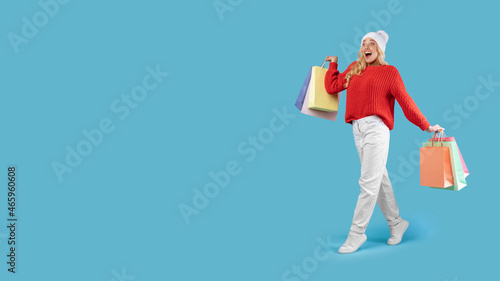 Excited blonde woman walking with shopping bags at studio