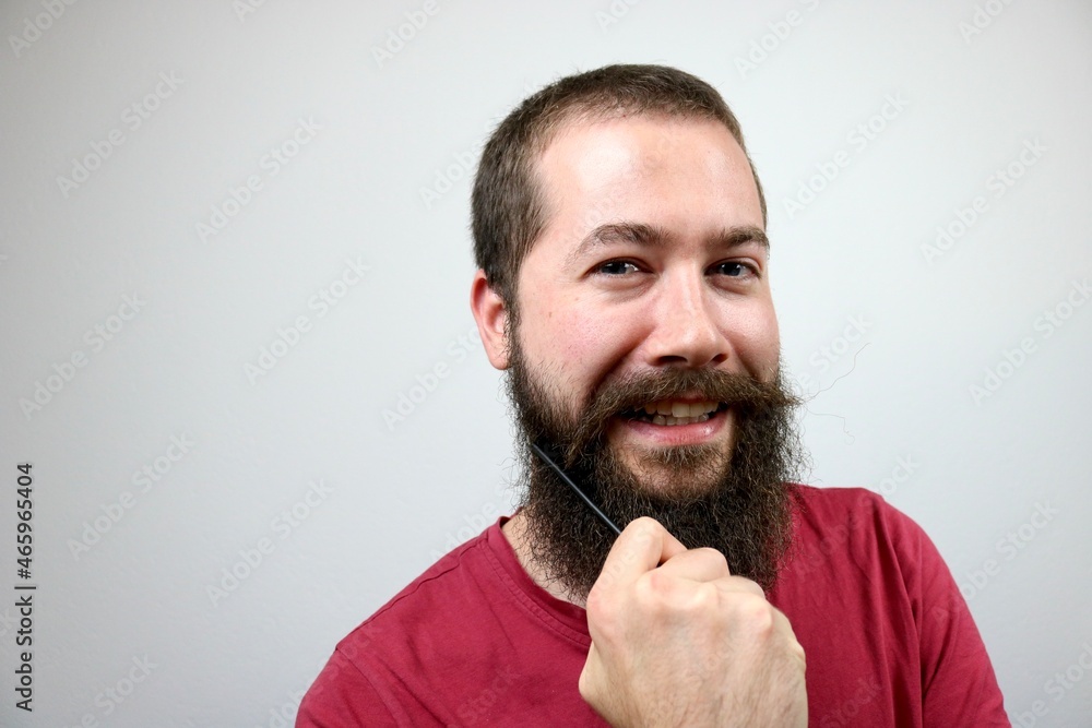Fototapeta premium Young caucasian man combing his beard
