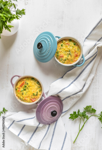 vegetables souffle on le creuset ceramic pots. white table and fresh parsley photo