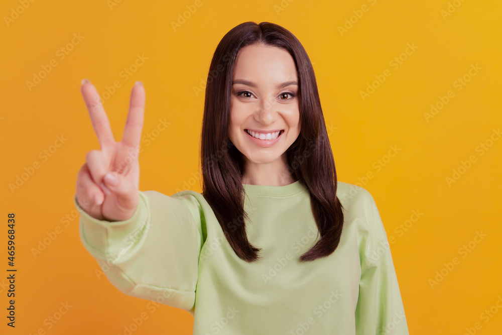 Photo portrait of young cheerful girl showing v-sign cool peace isolated bright yellow color background Photo portrait of young cheerful girl showing v-sign cool peace isolated bright yellow color background