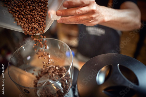 Canvastavla Close-up of barman hands holding a container and pouring coffee beans into a grinder apparatus