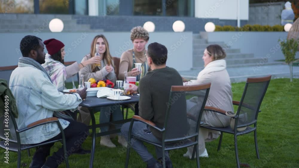 Smiling multinational friends celebrating something and clinking glasses outdoors Smiling multinational friends celebrating something and clinking glasses outdoors
