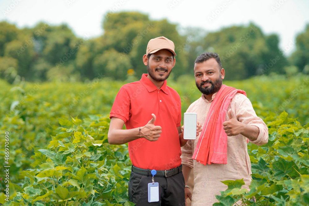 Fototapeta premium Indian farmer showing smartphone with agronomist or officer at agriculture field.