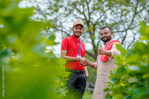 Young indian agronomist or banker shake hand with farmer at agriculture field.
