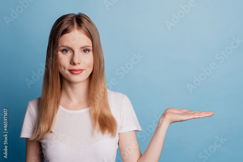 Portrait of confident promoter lady hand demonstrate empty space wear white t-shirt isolated on blue color background