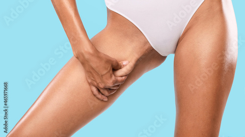 Unrecognizable young woman pinching her inner thigh, examining cellulite