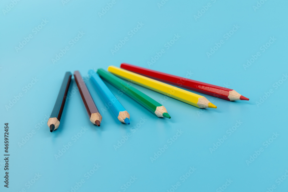 Six colored pencils close-up on a blue background with a copy of the space. The texture of bright colored wooden pencils.