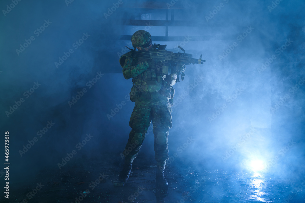 Portrait of airsoft player in professional equipment with machine gun in abandoned ruined building. Soldier with weapons at war in smoke and fog Portrait of airsoft player in professional equipment with machine gun in abandoned ruined building. Soldier with weapons at war in smoke and fog