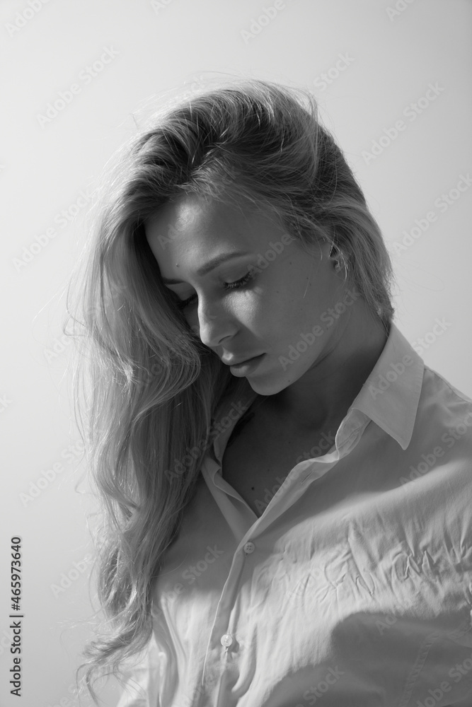 Close up black white portrait of sexy blond young woman in white mens shirt posing at home, beautiful girl with tousled hair studio shot