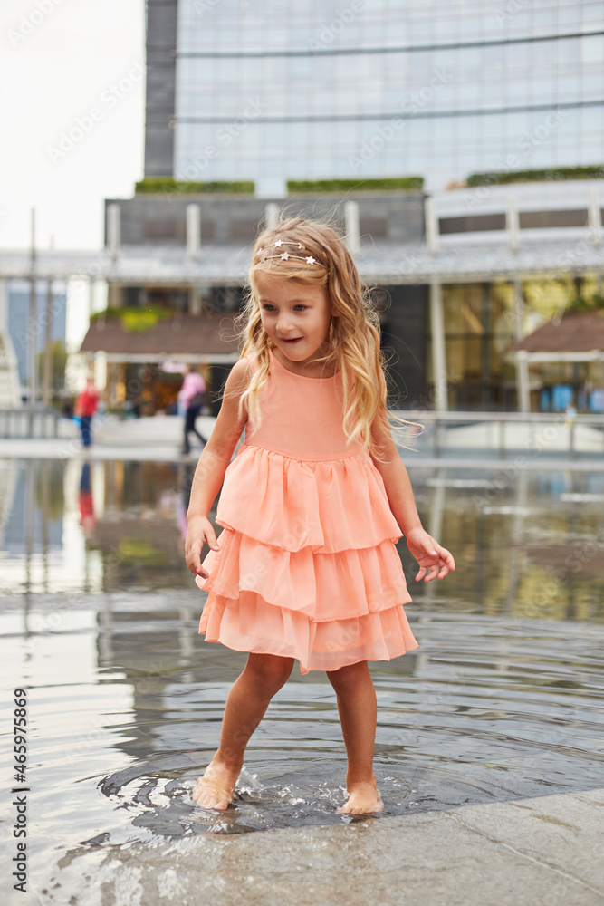 happy baby girl play with water in a fountain on the square happy baby girl play with water in a fountain on the square