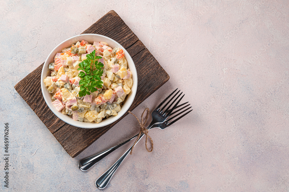 Classic olivier salad with fresh parsley on a light pink background. Top view, copy space. Classic olivier salad with fresh parsley on a light pink background. Top view, copy space.