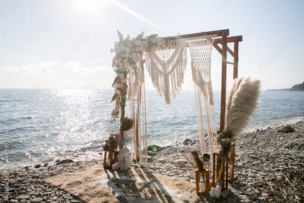 arch design with flowers and macrame for a photo shoot of a wedding ceremony at sunset on the seashore