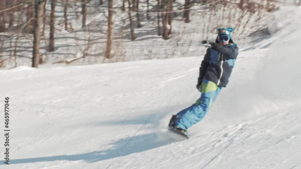 Snowboarder performs an ollie frontside 180 trick and falls on the slope on sunny winter day at a ski resort. Snowboard buttering tricks. Snowboarder performs an ollie frontside 180 trick and falls on the slope on sunny winter day at a ski resort. Snowboard buttering tricks.