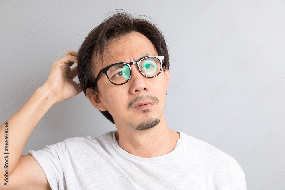 Asian man wearing eyeglasses with surprise and wonder expression on grey background. Asian man wearing eyeglasses with surprise and wonder expression on grey background.