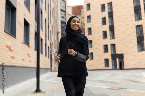 Outdoor Sports. Young Muslim Lady In Modest Sportswear Jogging On City Street © Prostock-studio