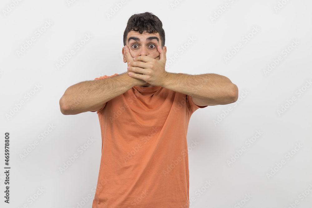 a boy covering his mouth with both hands because he does not want to scream on a white background. a boy covering his mouth with both hands because he does not want to scream on a white background.