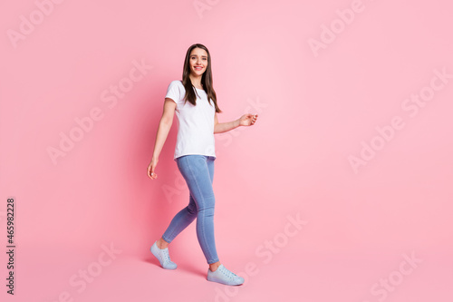 Full length body size photo girl happy smiling going forward isolated pastel pink color background