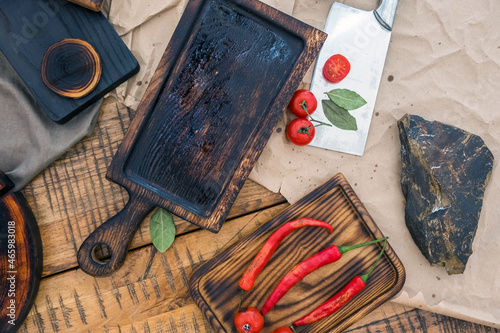 Fresh cherry tomatoes and spices on the wood and a chef's knife on the light surface of the table.