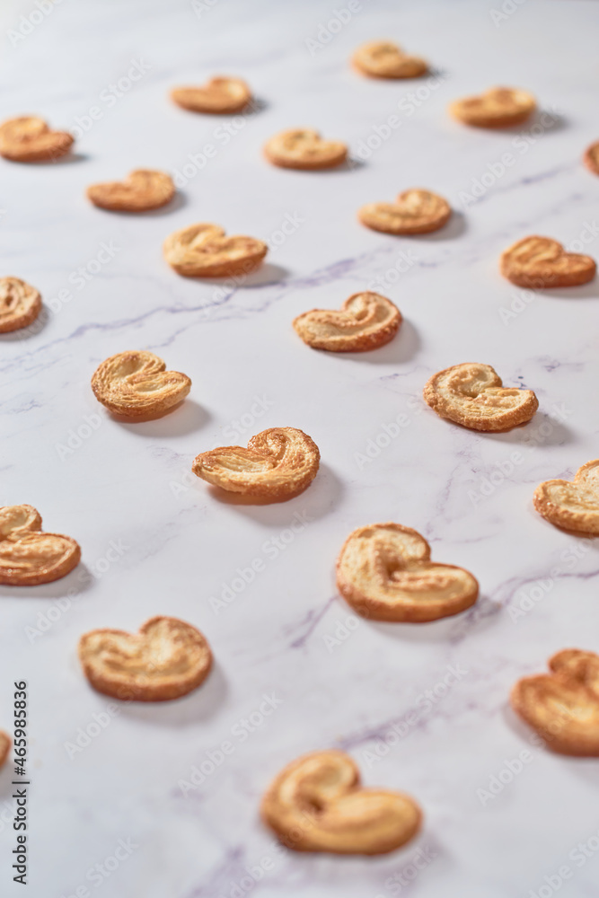 Set of Palmier puff pastry cookies or elephant ears on white marble table.